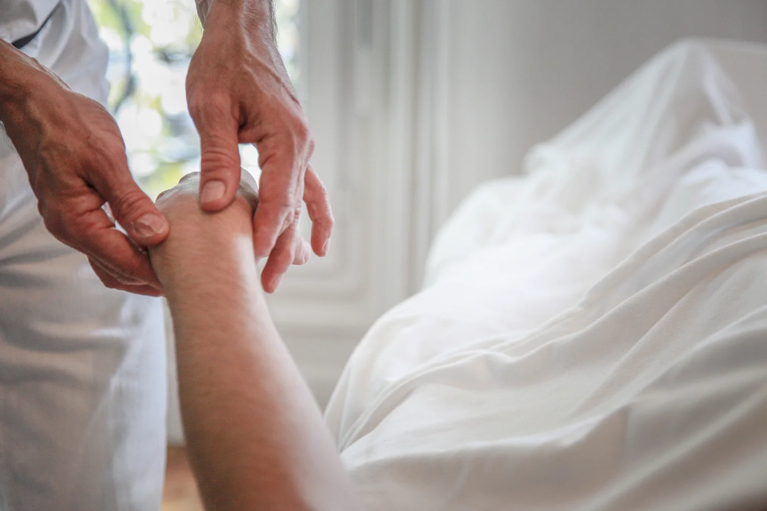 Mains pos&eacute;es sur l&rsquo;avant-bras d&rsquo;une personne pendant une s&eacute;ance au cabinet